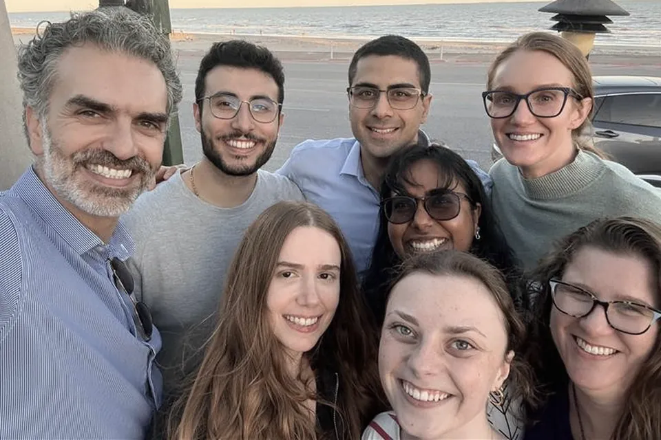 Eight members of the lab outdoors by the water in Galveston